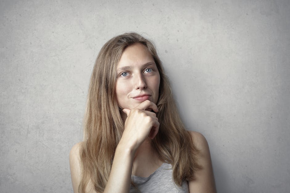 A thoughtful woman contemplates life in a simple portrait with a gray background.