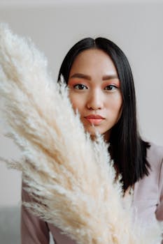 Close-up portrait of a woman with black hair holding pampas grass, perfect for lifestyle imagery.