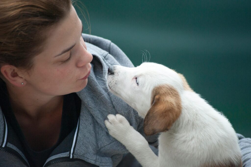 A candid shot of a woman and puppy sharing a tender moment outdoors.