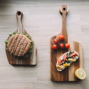 Aerial shot of a sesame seed burger and vegetable bruschetta on wooden boards, perfect for food photography.