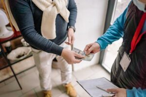 Close-up of hands exchanging cash during a transaction indoors, highlighting payment details.